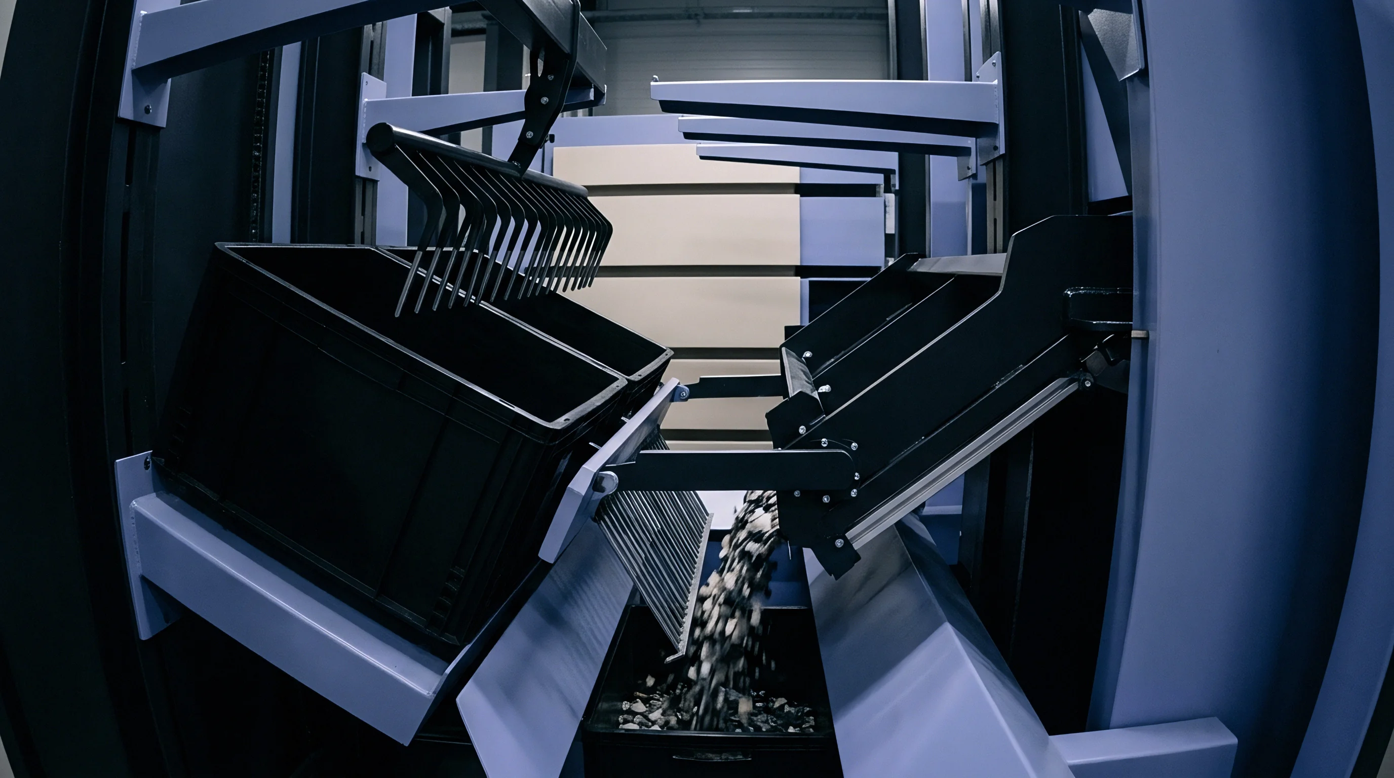 An industrial automated sorting machine discharges small metal parts from a tilted black plastic bin into a lower receptacle.